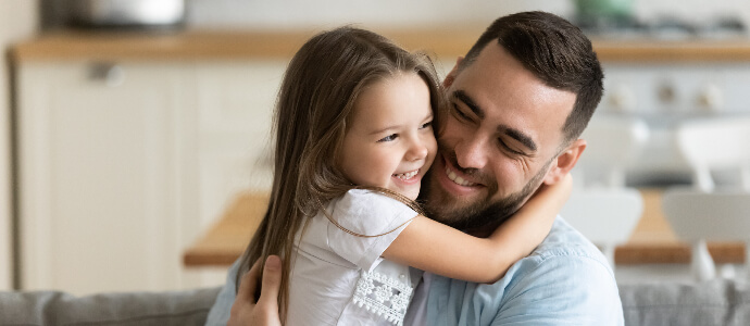 Close up smiling loving young father hugging adorable little daughter, child support