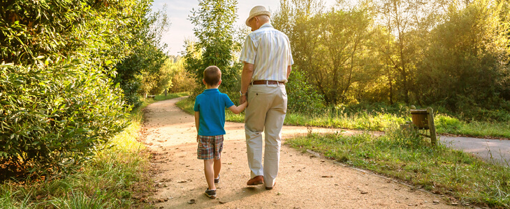 A grandfather walking in the park with his grandson