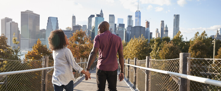 Young married couple walking with the New York City skyline in the background