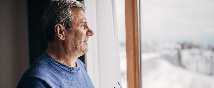 Man looking out the window while enjoying retirement