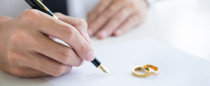 A man signs a document with rings placed on document