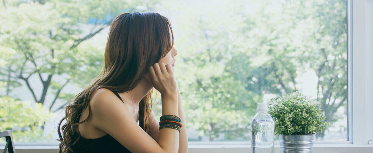 Young woman sitting and peering out the window.