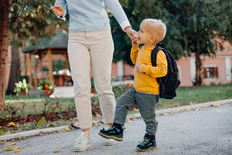 Mother holding the arms of her child while going to school