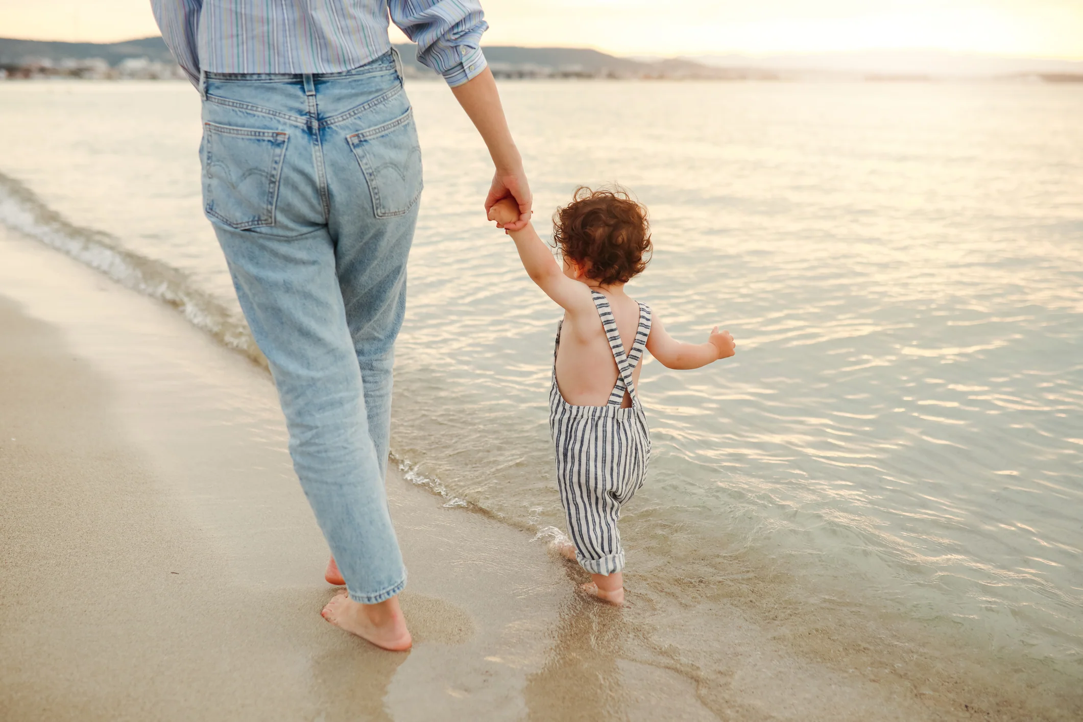 "Child custody concept with parent and child walking on beach holding hands."